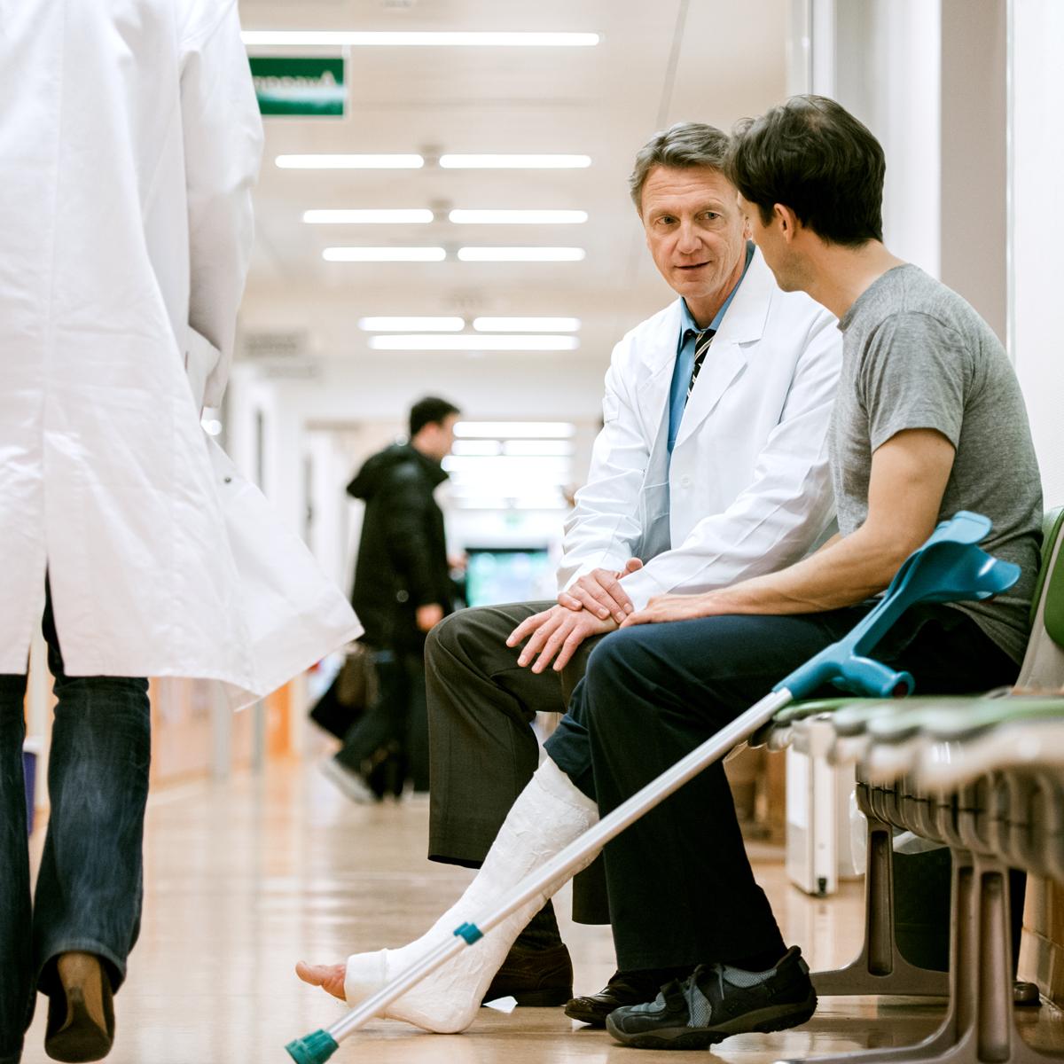 一名拄着拐杖的男子在医院走廊与医生交谈.